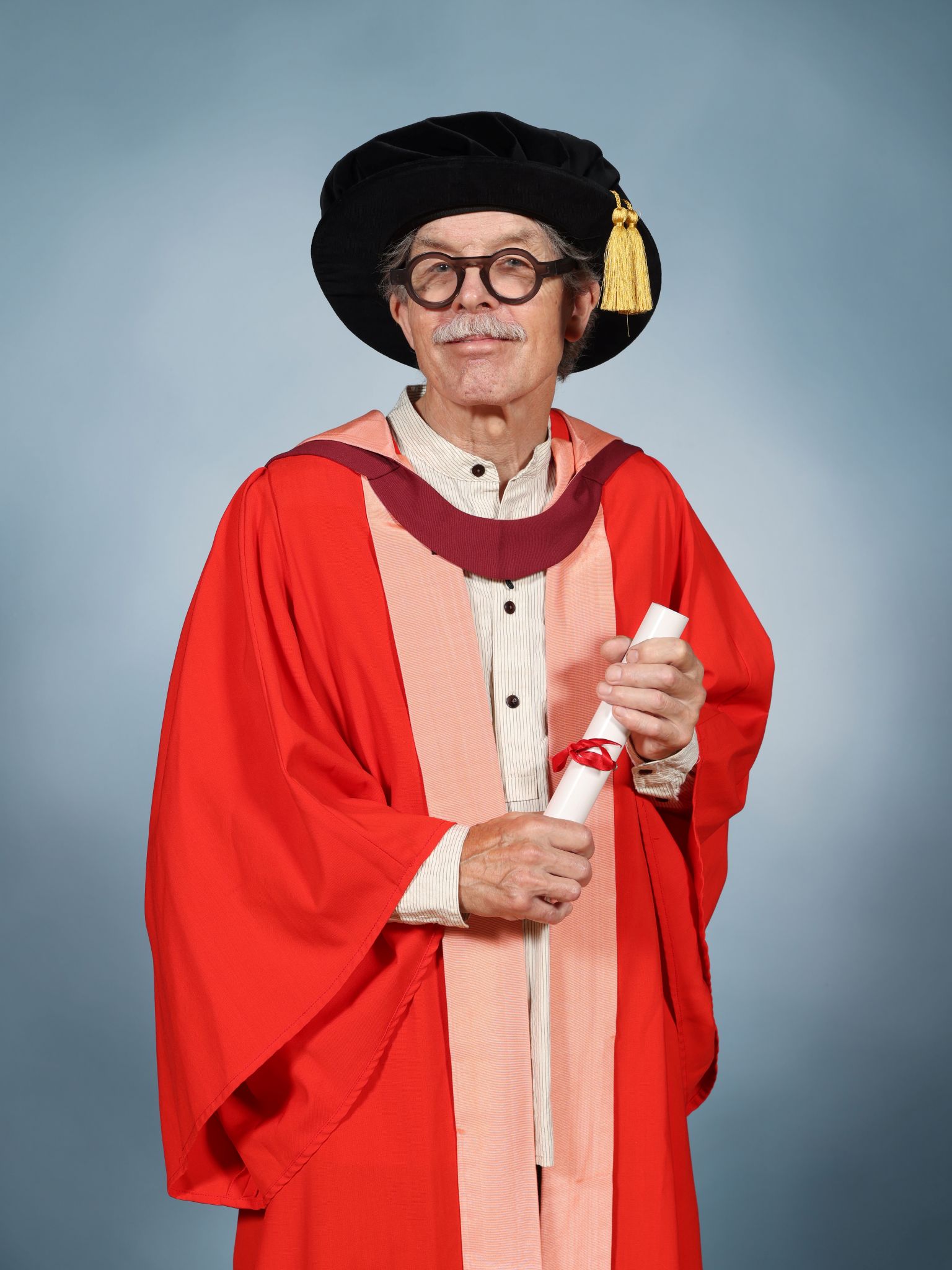 Simon Carpenter wearing a mortar board and holding a parchment